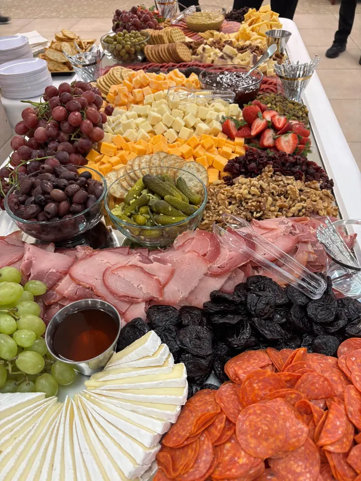 A large charcuterie board with cheeses, cured meats, fruit, and nuts at a catered event