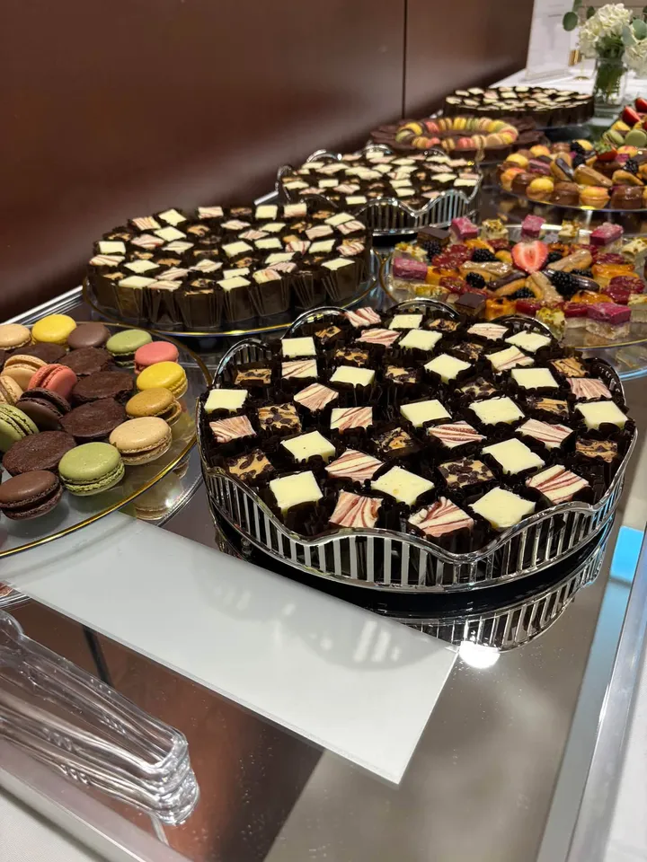 Trays of petit fours, macarons, and berry pastries on a dessert table