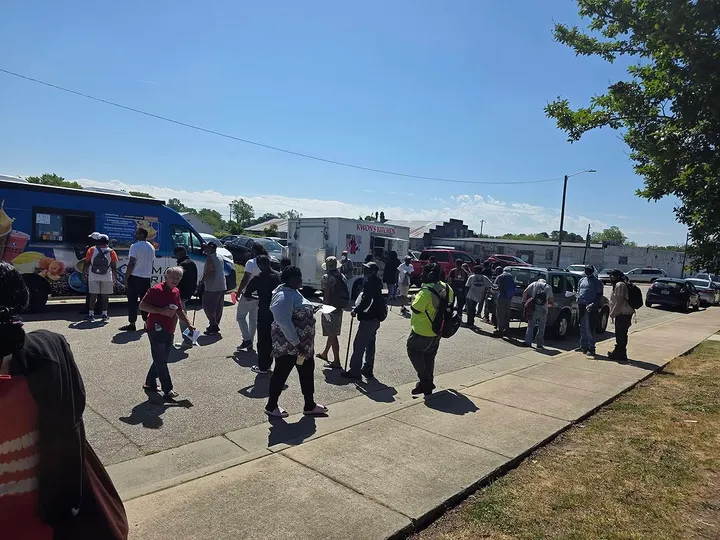A line of neighbors waiting at food trucks during a community resource fair