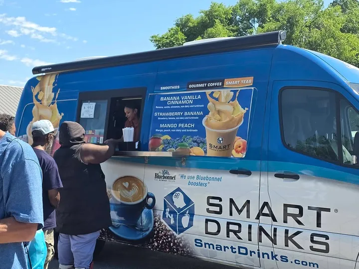A volunteer serving drinks from a Smart Drinks truck to attendees at a resource fair