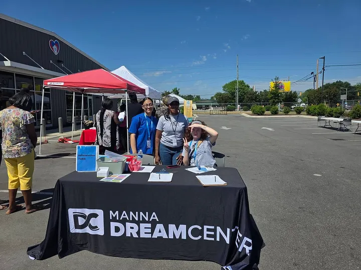 Volunteers smiling behind an information table at a community resource fair