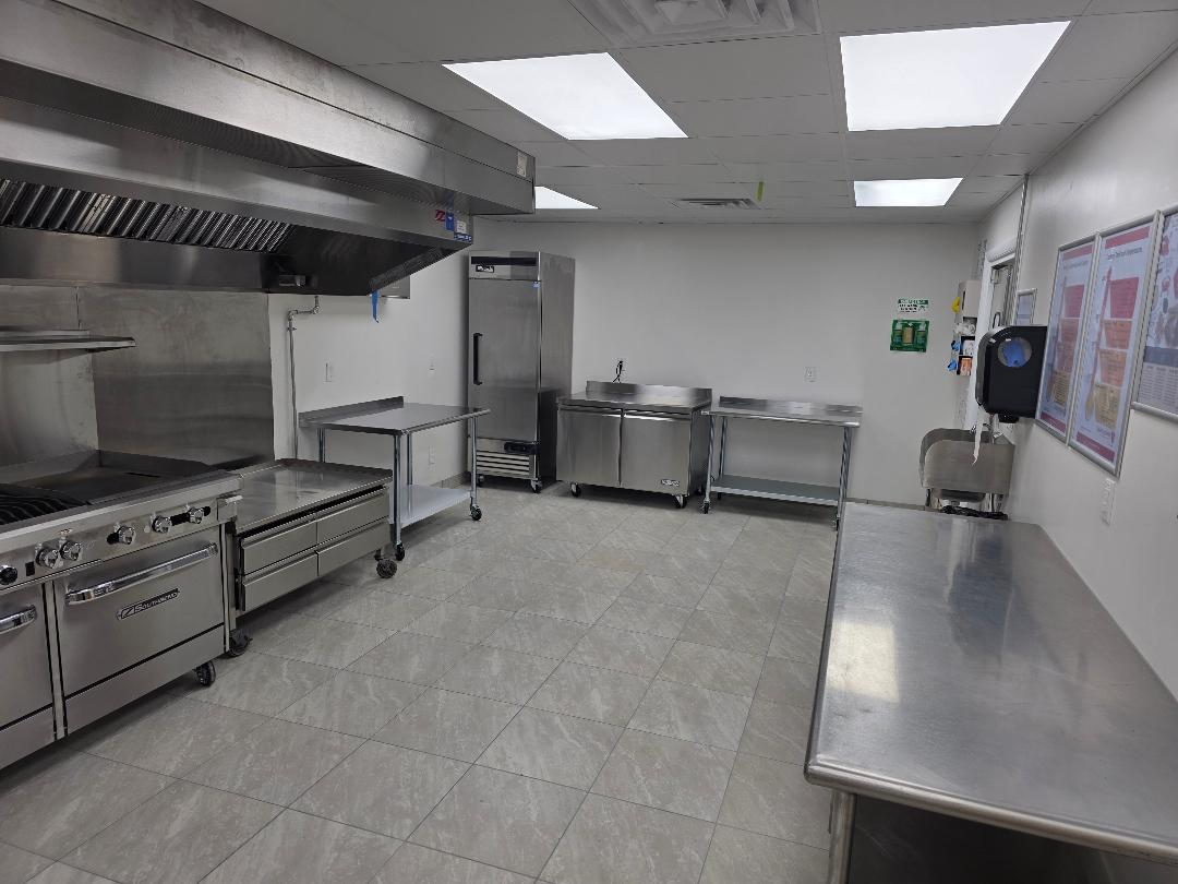 A private commercial kitchen with range, hood and stainless prep benches