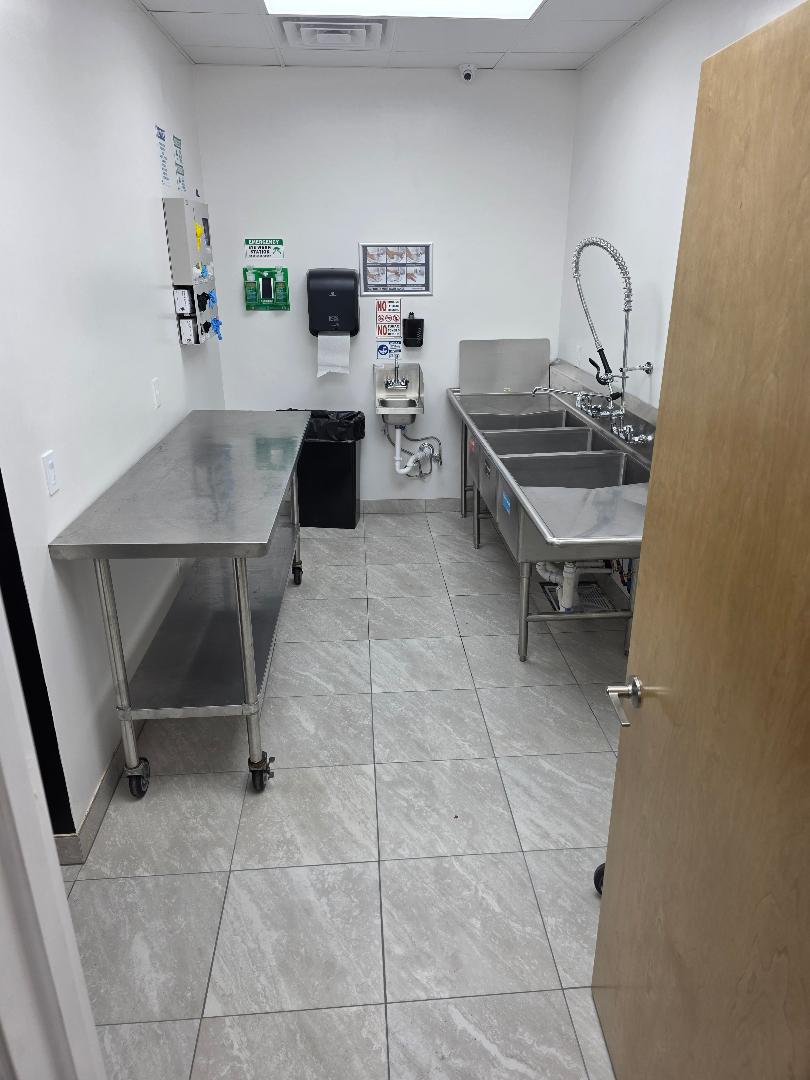 A prep room with a stainless bench and a three compartment sink